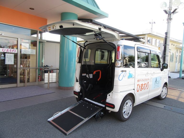介護施設の玄関前に停車する車椅子対応の送迎車両。リフト機能付き。